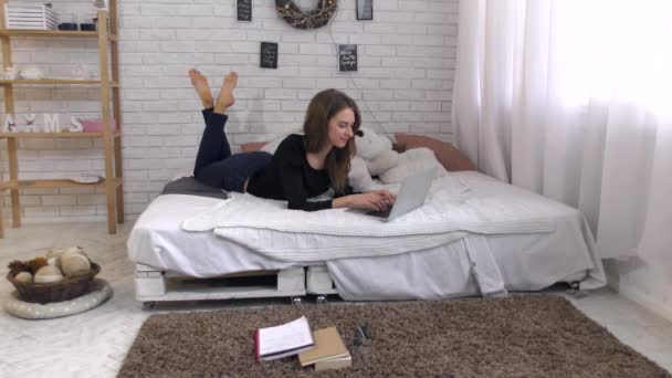 Молодая женщина работает с ноутбуком на кровати — стоковое видео