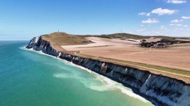 Explore the breathtaking aerial perspective of Cap Blanc Nez, revealing the dramatic cliffs, turquoise waters, and surrounding farmlands of northern France. Ideal for nature lovers.