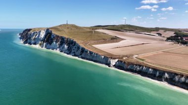 Discover magnificent cliffs and vibrant waters at Cap Blanc Nez, France. This aerial exploration showcases the dramatic coastal beauty and lush surroundings during clear weather.