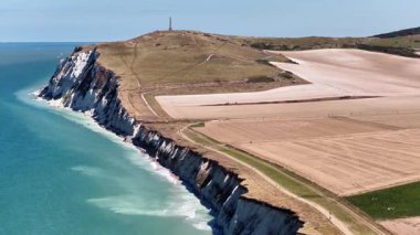 Experience breathtaking aerial views of Cap Blanc Nez in France, showcasing dramatic cliffs, serene waters, and expansive landscapes under a clear blue sky. Natures beauty unfolds.