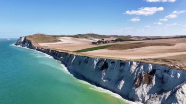 Experience the breathtaking aerial views of Cap Blanc Nez in France. This location features striking white cliffs overlooking the azure waters, surrounded by rolling agricultural fields.