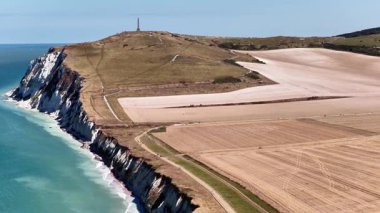 This aerial perspective reveals the breathtaking cliffs of Cap Blanc Nez, where the coastline meets serene blue waters. Expansive fields stretch across the landscape, highlighting natural beauty.