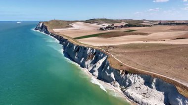 Experience breathtaking aerial views of Cap Blanc Nez in northern France, featuring dramatic cliffs, tranquil ocean waters, and lush green landscapes under a clear sky.
