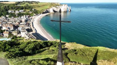 Experience the breathtaking aerial view of Etretat in France. The stunning white cliffs rise above the beach and turquoise waters, revealing the charm of this coastal gem.
