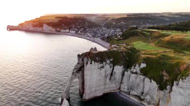 Discover the stunning aerial view of the Etretat cliffs in France during sunset. Experience the vibrant colors and dramatic landscapes of this coastal gem.