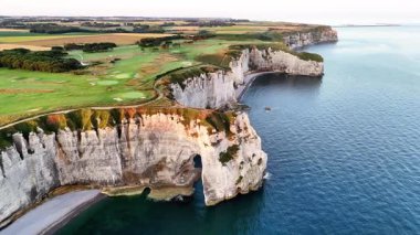 Explore the breathtaking cliffs of Etretat, France, captured from above at sunrise. The stunning rock formations and the calm sea create an unforgettable landscape.