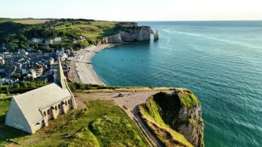 Explore the breathtaking cliffs and serene beach of Etretat in France from an aerial perspective. Marvel at the stunning coastal scenery and natural beauty of this iconic location.
