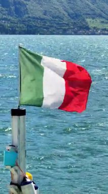 Enjoy the gentle waves of Lake Como as the vibrant Italian flag waves in the breeze. Experience the beauty of Italys lakeside charm and peaceful surroundings.