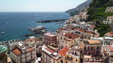 Experience breathtaking views of the Amalfi Coast, showcasing vibrant coastal homes, serene waters, and boats scattered along the shore. This captivating landscape shines under the clear sky.