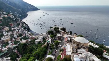 Experience the breathtaking aerial perspective of Positano, Italy, where charming houses cling to cliffs and the serene coastline meets the sparkling sea. This coastal gem offers stunning views.