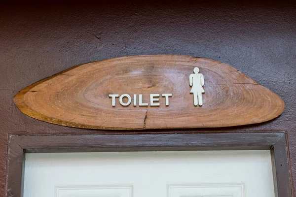 白色门上棕色混凝土墙壁上的木制厕所标签 — 图库照片