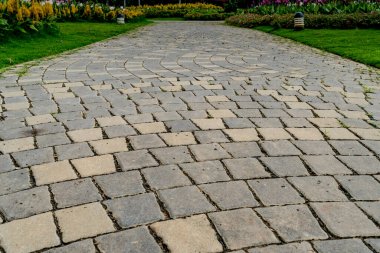 Parkta renkli çiçekler olan beton blok yolu.