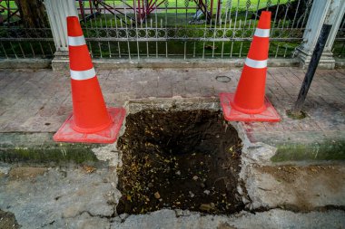 Asfalt yolundaki çukurda plastik turuncu koni.