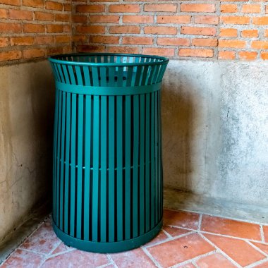 Kahverengi tuğla duvar arka planında yeşil metal çöp kutusu