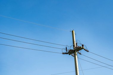 Mavi gökyüzü arka planında elektrik hatları ve beton direk