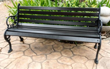 Bahçede beton zeminde ahşap park bankı