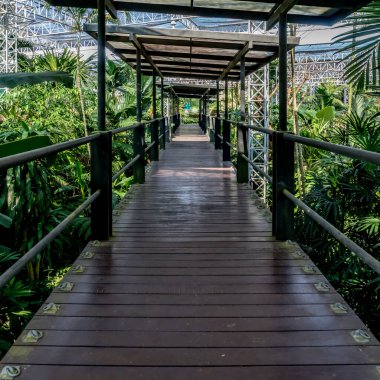 Parkta demir parmaklıklar olan tahta patika köprü.