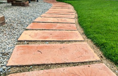 Parkta yeşil çimenli kahverengi beton patika.