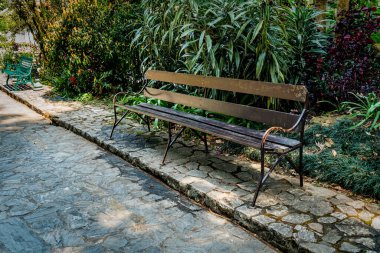 Bahçedeki beton zeminde ahşap parktaki bank