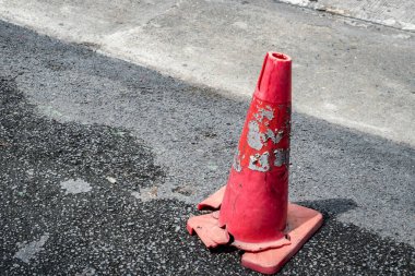Asfalt yolda kırık kırmızı plastik koni.