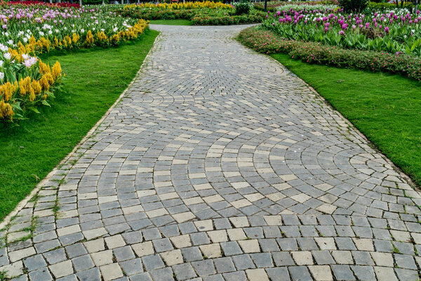 Concrete block pathway with colorful flowers in the park