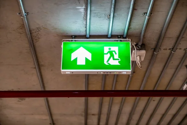 Green Emergency exit sign with metal pipes