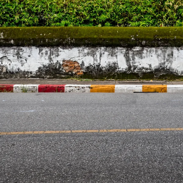人行道路边有黄红白两色交通标志的沥青路面及旧的白混凝土围栏 — 图库照片