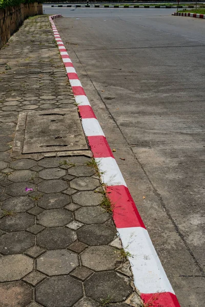 Concrete block sidewalk with Red and white concrete curb