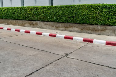 Beton yolu ve kırmızı beyaz tabelası olan yeşil çit.