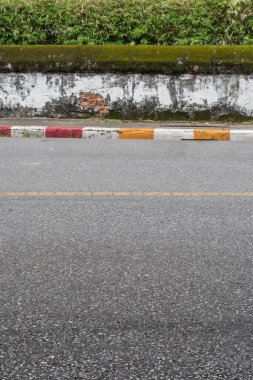 Asfalt yolu, kaldırım kenarında sarı kırmızı ve beyaz trafik işareti ve eski beyaz beton çit.