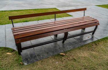 Parkta yeşil çimen olan ahşap parktaki bank