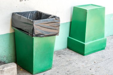 Beton duvar arka planında yeşil çöp kutusu