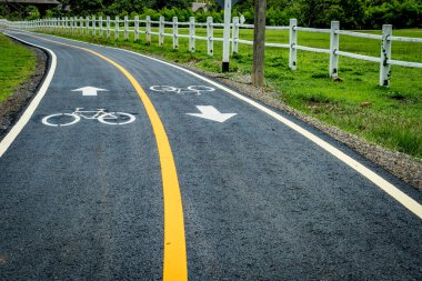 Asfalt bisiklet yolu. Sarı çizgi ve bisiklet yolu işareti var.