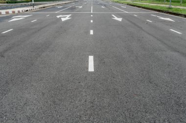 Ok işareti ve beyaz nokta çizgisi olan asfalt yolu