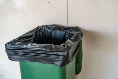 Beton duvar arka planında yeşil çöp kutusu