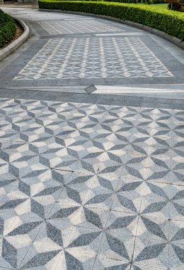 Parktaki çimento yolu yeşil çitlerle süslenmiş.