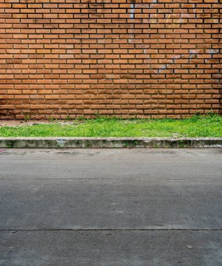 Yeşil çimenli ve beton yolu olan eski kahverengi tuğla duvar.