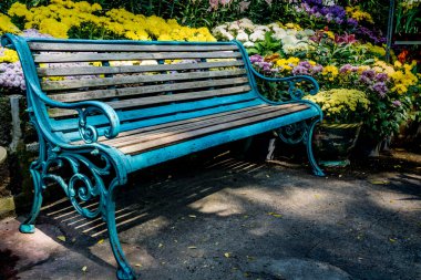 Parkta renkli çiçeklerle beton zeminde park bankı