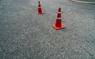 Asfalt yolda iki turuncu plastik koni.