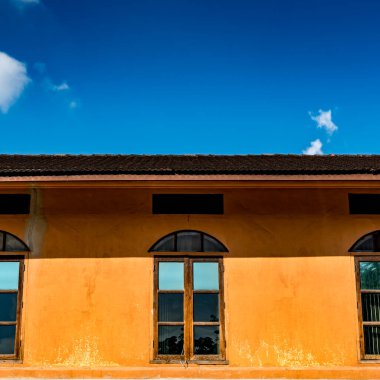 Mavi gökyüzü arkaplanlı kahverengi beton duvardaki pencereler