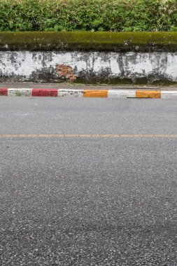Asfalt yolu, kaldırım kenarında sarı kırmızı ve beyaz trafik işareti ve eski beyaz beton çit.