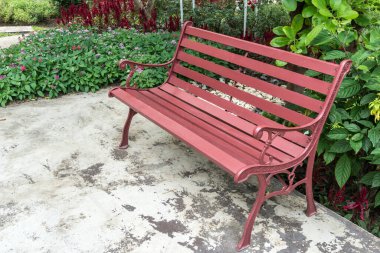 Bahçede beton zeminde ahşap park bankı