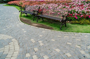 Parkta renkli çiçekleri olan metal park bankı