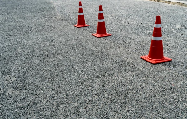 Three orange plastic cones on the asphalt road
