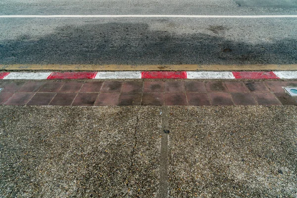 Asphalt road and Concrete sidewalk with Red and white concrete curb