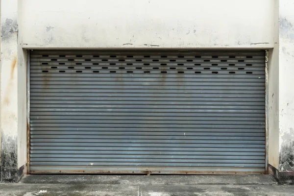 Old gray roller shutter door on white concrete wall