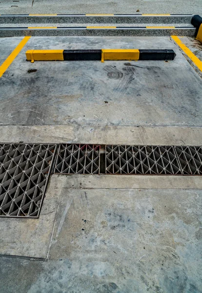 Pusty Parking Czarno Żółtym Betonowym Krawężnikiem Metalową Pokrywą Odpływową — Zdjęcie stockowe