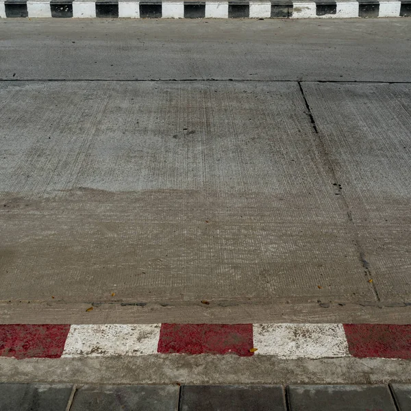Concrete road with Black and white with red and white concrete curb