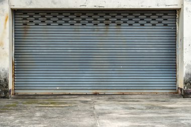 Paslı, gri kapaklı, beton zeminli kapı.