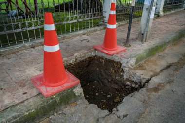 Asfalt yolundaki çukurda plastik turuncu koni.